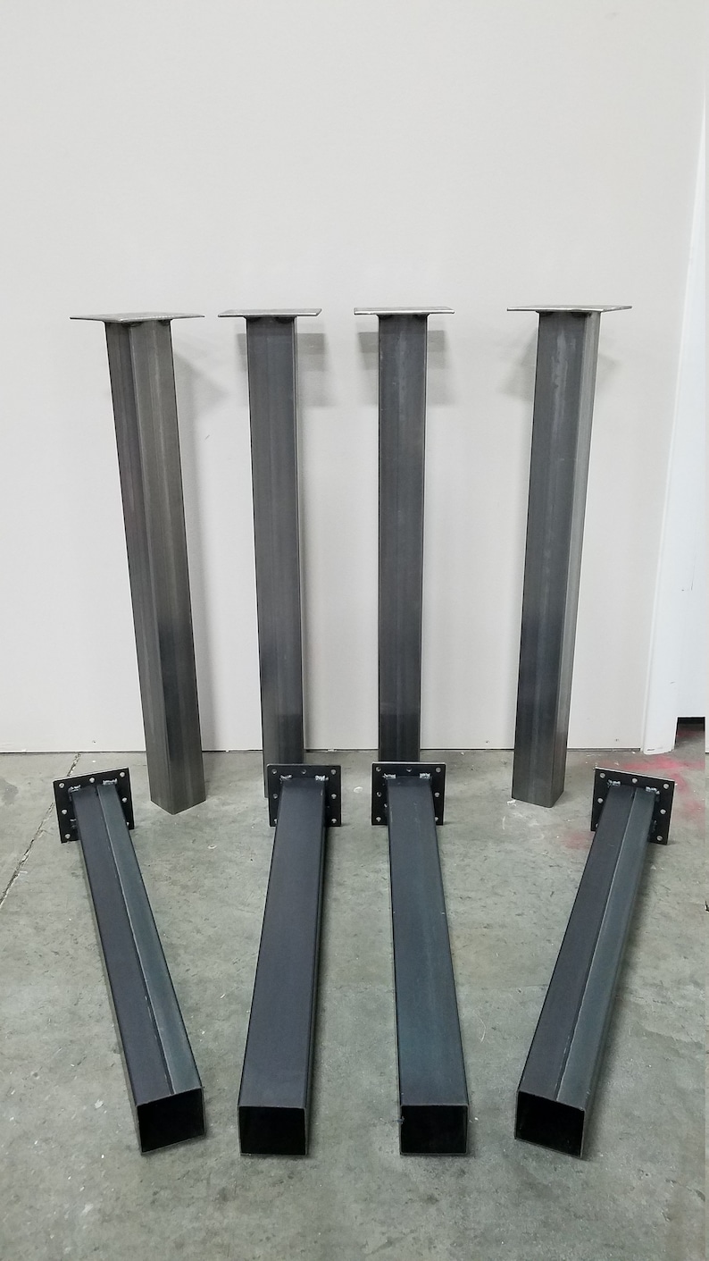 May include: Set of eight metal table legs. The legs are square in shape and have a black finish. The legs are arranged in two rows of four.