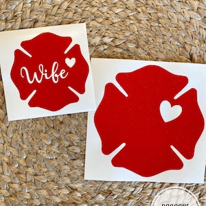 May include: Two red firefighter's helmet decals. One decal says "Wife" with a small white heart. The other decal has a white heart.