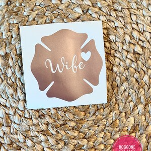 May include: A rose gold firefighter's helmet decal with the word "Wife" and a white heart.