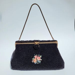 Pode incluir: Uma bolsa de noite preta de contas com fecho dourado e um design de bordado floral.