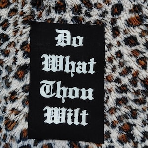 Könnte beinhalten: Schwarzer Patch mit weißem Text in alter englischer Schrift, der "Do What Thou Wilt" lautet.