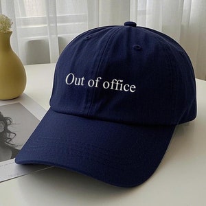 Może przedstawiać: Czapka bejsbolowa w kolorze granatowym z białym haftem z napisem "Out of office".