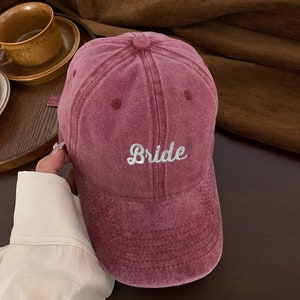 Puede incluir: Una gorra de b&eacute;isbol de color burdeos con la palabra "Bride" bordada en blanco en la parte delantera.