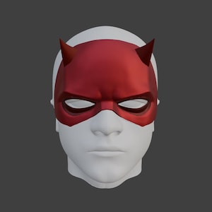 Op de afbeelding: Een rood superheldenmasker met puntige hoorns en ooggaten, tegen een wit gezicht en een grijze achtergrond. Het masker heeft een levendige rode kleur en de hoorns zijn scherp gedefinieerd. Het ontwerp suggereert een stripboek- of cosplay-thema.