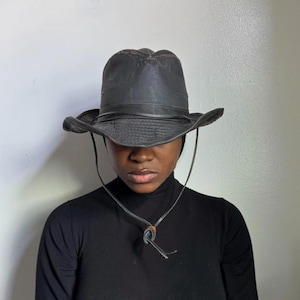 May include: A white ceramic mug with a black handle and the text "But First, Coffee" in a bold, black font. The mug is set against a blurred background, suggesting a cozy setting.