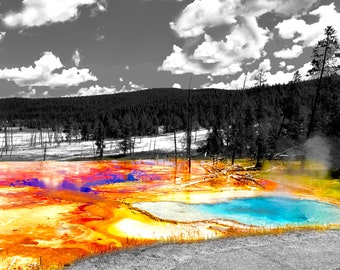 May include: A colorful hot spring in a natural landscape. The water is a vibrant blue, surrounded by orange and yellow hues. The surrounding area is in black and white, highlighting the colorful spring.