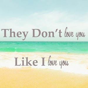 May include: A beach scene with blue water and white waves crashing on the shore. The text "They Don't love you Like I love you" is written on the sand.