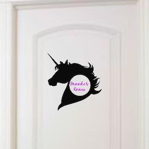 Könnte beinhalten: Schwarze Silhouette eines Einhornkopfes mit einem weißen Kreis, auf dem in lila Farbe "Brookes Zimmer" steht, auf einer weißen Tür.