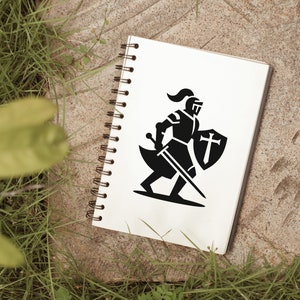 Op de afbeelding: Een zwart-witte illustratie van een ridder in harnas met een zwaard en schild met een kruis erop. De illustratie is getekend op een wit notitieboek.