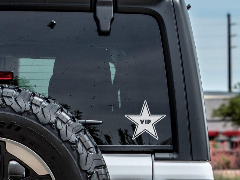 May include: A white star-shaped sticker with the word "VIP" inside, on the rear window of a black car.