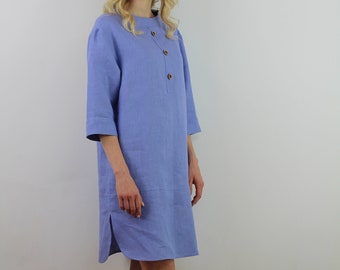 May include: A light blue linen dress with a button-up front and three-quarter sleeves. The dress has a relaxed fit and a slightly A-line silhouette.