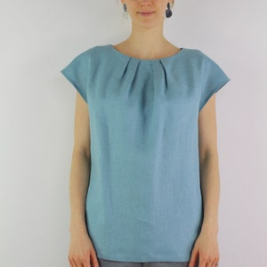 May include: A light blue linen top with a gathered neckline and short sleeves.