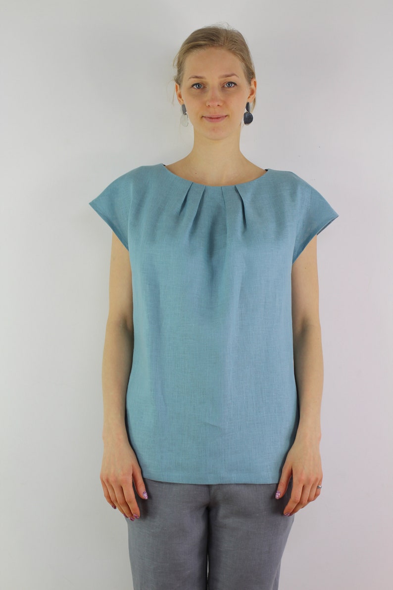 May include: A light blue linen top with a gathered neckline and short sleeves.