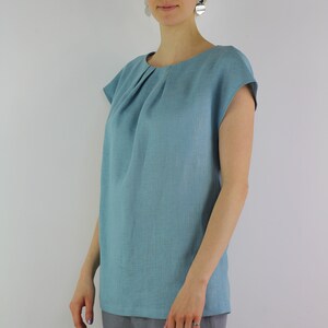 May include: A light blue linen top with a gathered neckline and short sleeves.