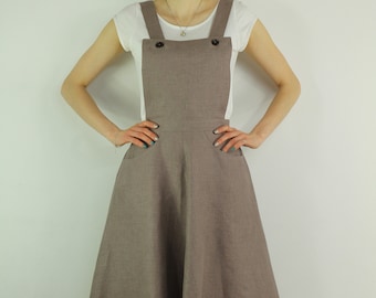 May include: A brown linen overall dress with a white sleeveless top underneath. The dress has a fitted bodice and a full skirt.