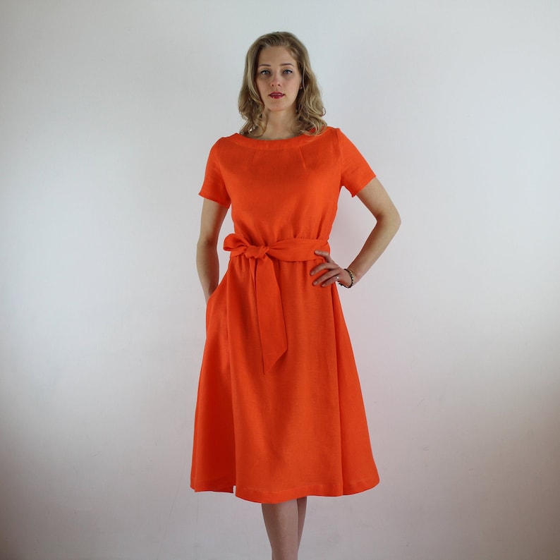 May include: A bright orange linen dress with a short sleeve, a scoop neck, and a self-tie belt.