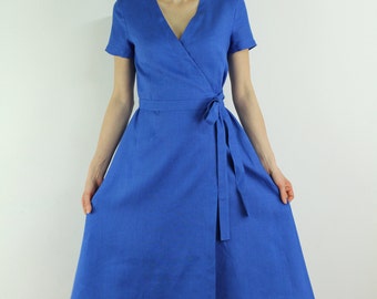May include: A blue wrap dress with short sleeves and a tie belt. The dress has a v-neckline and a flared skirt.