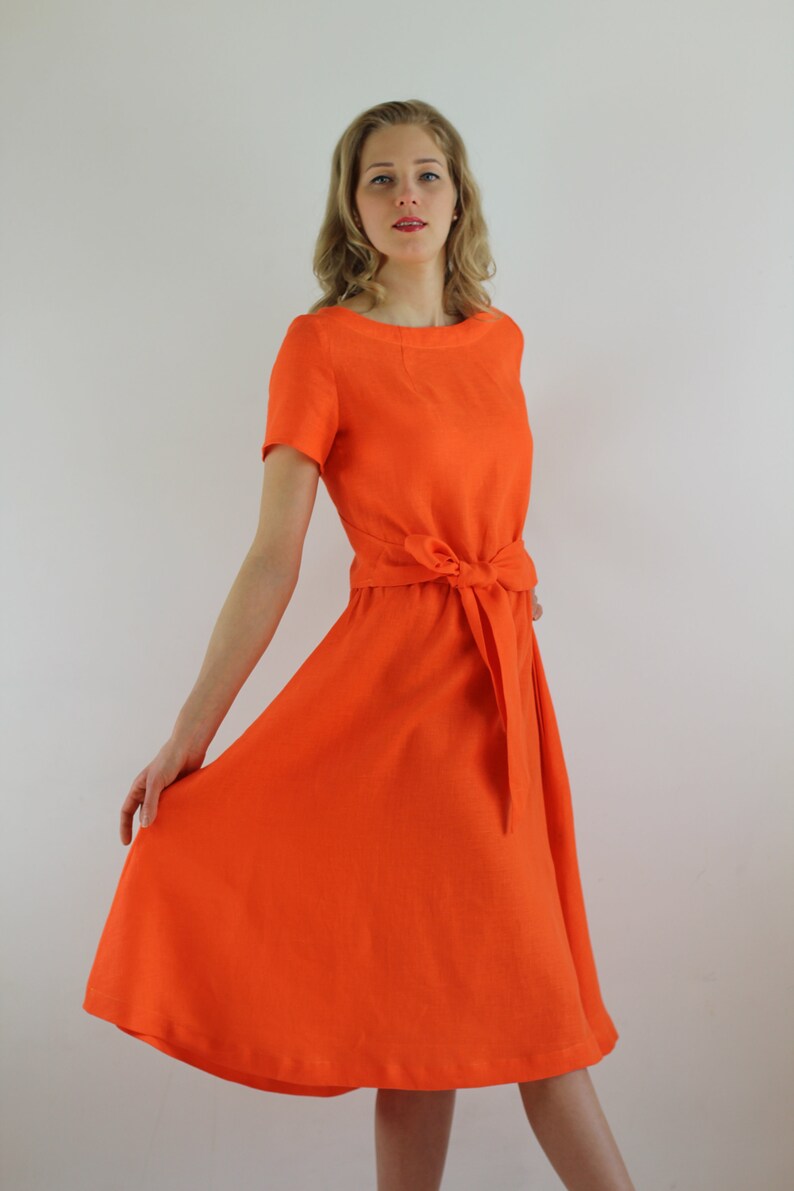 May include: A bright orange linen dress with a short sleeve and a tie at the waist.