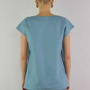 May include: A light blue linen top with short sleeves and a scoop neck.