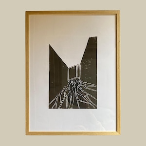 Op de afbeelding: Een zwart-witte print van een boek met wortels die eruit groeien. Het boek bevindt zich in een donkere, schaduwrijke ruimte.