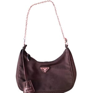 May include: A dark brown nylon Prada Re-Edition 2001 shoulder bag with a silver chain strap and a small leather tag that says "Prada Re-Edition 2001".
