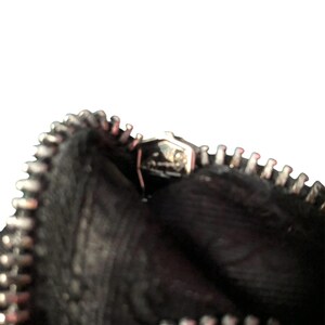 May include: Close-up of a black zipper on a bag. The zipper is open and the inside of the bag is visible.