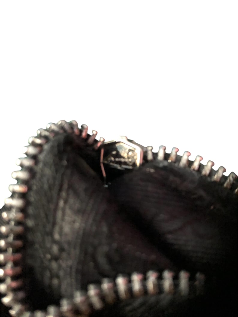 May include: Close-up of a black zipper on a bag. The zipper is open and the inside of the bag is visible.