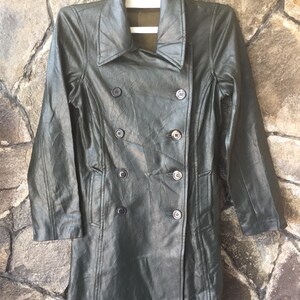May include: A long, dark green, faux leather coat with a double-breasted button closure. The coat has a collar and two pockets.