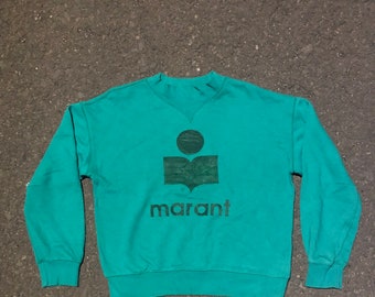 Puede incluir: Una sudadera de color verde azulado con un logotipo verde oscuro y la palabra "marant" impresa en la parte delantera.