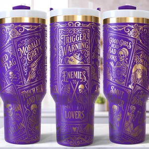 May include: Purple travel tumbler with gold-colored illustrations and text. The tumbler features phrases like "Trigger Warning" and "Enemies to Lovers." The design includes images of skeletons, guns, and playing cards. It has a purple handle and a white and gold lid.