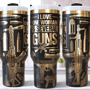 Könnte beinhalten: Schwarzer Reisebecher mit goldfarbenen Illustrationen von Waffen und Munition. Der Becher hat einen weißen Deckel und einen schwarzen Griff. Auf dem Becher steht "I LOVE ONE WOMAN & SEVERAL GUNS".