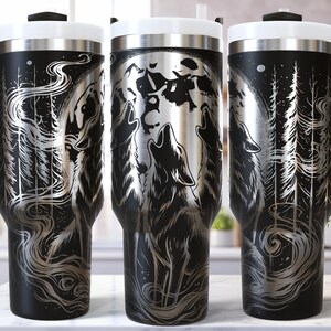 May include: Black and silver insulated tumbler featuring a wolf howling at the moon, surrounded by a forest scene. The tumbler has a black handle, a white lid, and a silver interior. The design is etched onto the tumbler.