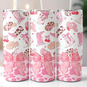 May include: Three stainless steel tumblers with a pink cowgirl theme. The design features pink cowboy boots, hats, and bows on a white background. The bottom of the tumblers have a pink cow print and a large pink bow.