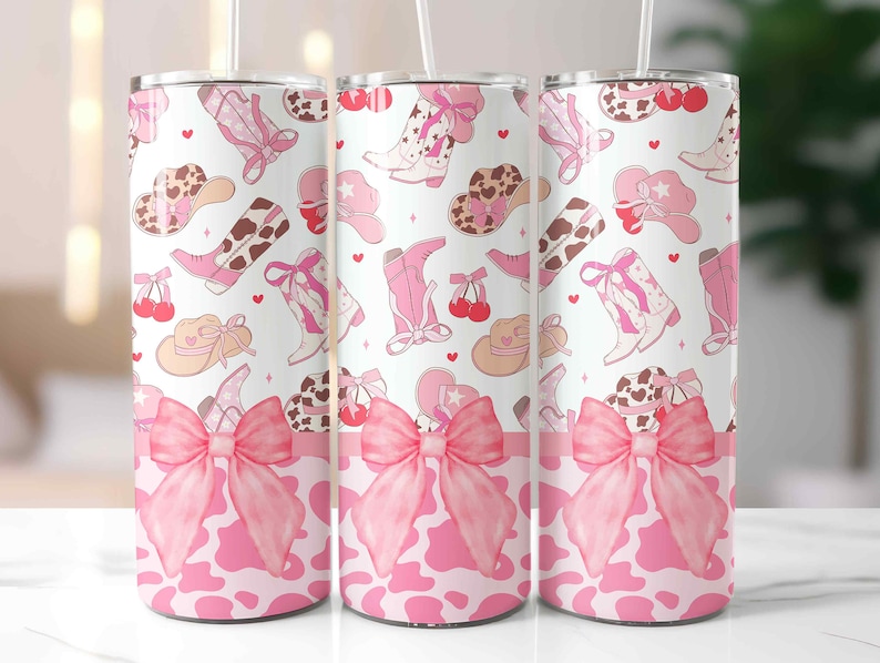 May include: Three stainless steel tumblers with a pink cowgirl theme. The design features pink cowboy boots, hats, and bows on a white background. The bottom of the tumblers have a pink cow print and a large pink bow.