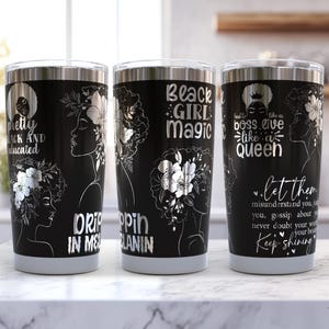 Könnte beinhalten: Drei schwarze Edelstahlbecher mit silbernem Text und Illustrationen. Jeder Becher hat ein anderes Design, darunter Texte wie "pretty black and educated", "Black Girl Magic" und "live like a boss like a queen."