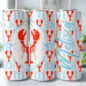 May include: A set of three stainless steel tumblers with a lobster design. The tumblers feature a repeating pattern of red lobsters on a white and light blue striped background. One tumbler has the name "Melissa" in light blue.