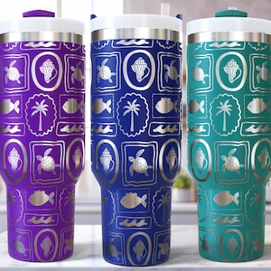 Könnte beinhalten: Drei isolierte Becher in Lila, Blau und Türkis, jeweils mit weißem Deckel und Griff. Die Becher weisen ein sich wiederholendes Muster aus Meereslebewesen und tropischen Elementen in Silber auf, darunter Schildkröten, Fische und Palmen.