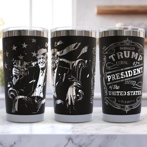 May include: Three black stainless steel tumblers with silver designs. One tumbler features a portrait of a man holding a glass, another shows a man in a chair, and the third displays text that reads "Donald Trump 47th President of the United States."