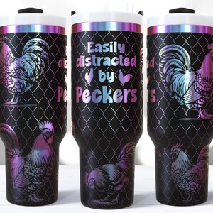 May include: Black travel mug with a handle, featuring a rooster design and the text "Easily distracted by Peckers." The rooster and text have a gradient of pink, blue, and purple. The mug has a black handle and a white lid.