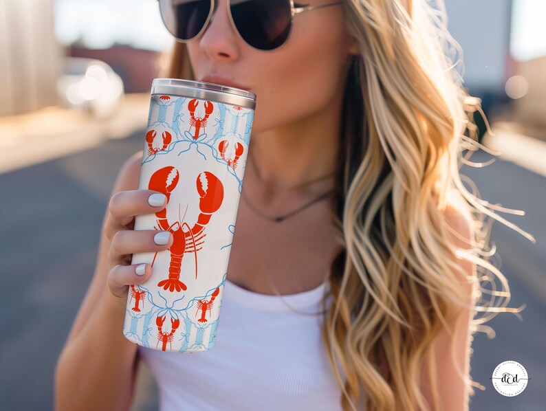 May include: A white tumbler with a red lobster design and blue accents. The stainless steel travel mug has a silver lid and is cylindrical in shape. The lobster pattern is repeated around the tumbler's surface.