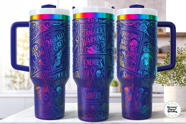 May include: A set of three insulated tumblers with a dark blue background and a wraparound design featuring book-themed graphics. The text includes "Trigger Warning", "Enemies to Lovers", and "Good Girls Read Bad Books". Each tumbler has a blue handle and a rainbow-colored rim.