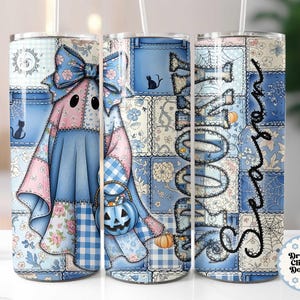 May include: A Halloween-themed tumbler featuring a patchwork design with a ghost character. The ghost is dressed in blue and pink patchwork with a bow, holding a pumpkin basket. The tumbler has the words "Spooky Season" in black script.