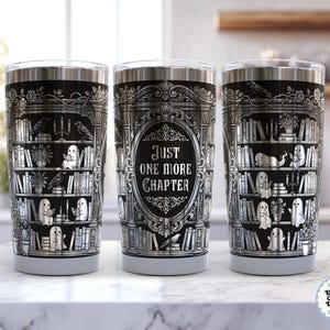 May include: Stainless steel travel mug featuring a black and silver bookshelf design. The design includes books, ghosts, and the text "Just One More Chapter". The mug has a silver lid and a grey base.