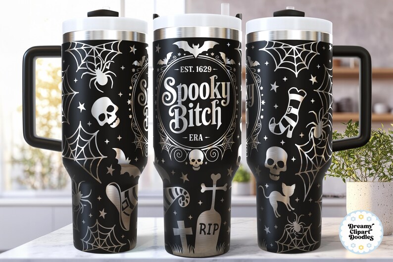 May include: Black travel mug with a white lid and handle, featuring a Halloween-themed design. The design includes spiderwebs, spiders, bats, skulls, and the text "Spooky Bitch - ERA".