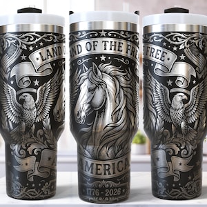 May include: Black and silver travel tumbler with a handle, featuring an eagle, horse, and the text "Land of the Free" and "America 1776-2026". The tumbler has a white lid and a black handle.