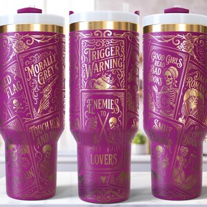 May include: Three purple travel mugs with gold accents and handles. Each mug features a unique design with text and illustrations, including phrases like "Trigger Warning" and "Good Girls Read Bad Books."