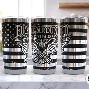 Op de afbeelding: Roestvrijstalen beker met een zwart en zilver design. De beker heeft een Amerikaans vlagontwerp, horizontale strepen en een adelaarsafbeelding met de tekst "FUCK AROUND & FIND OUT".
