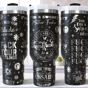 May include: Black stainless steel travel mugs with white lids and black handles. The mugs feature various silver text designs, including phrases like "Don't need your attitude" and "I'm a sarcastic bitch."