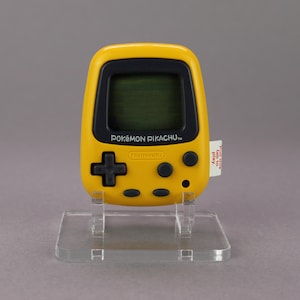 Könnte beinhalten: Ein gelbes, handliches elektronisches Spiel mit einem schwarzen Bildschirm und Knöpfen. Das Spiel ist mit "POKÉMON PIKACHU" und "Nintendo" beschriftet.