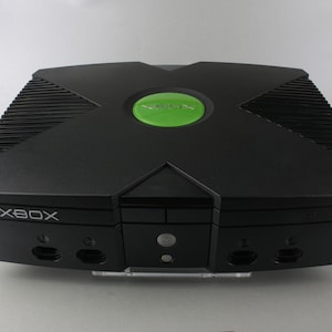 May include: A black Xbox console with a green power button and the word "XBOX" printed on the front.